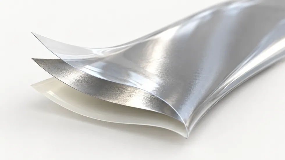 Curved multilayer packaging film with a clear glossy upper layer, a reflective silver middle layer, and a translucent white lower layer against a light background.